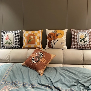 Detail of geometric plaid and floral print cushion covers on a modern headboard