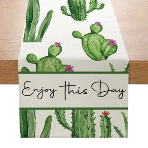 Détail du chemin de table en lin avec imprimés cactus et inscription Enjoy This Day