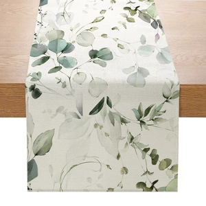 Détail du chemin de table en lin avec imprimé feuilles d'eucalyptus sur table en bois