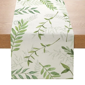 Détail du chemin de table en lin avec motif de feuilles vertes sur table en bois