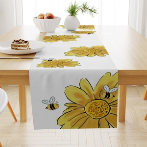 Detail of floral table runner with yellow sunflowers and bees on a wooden dining table