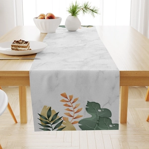Detail of tropical leaf pattern table runner on a wooden desk with home dining decor