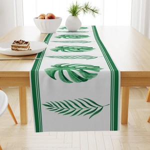 Detail of tropical green leaf patterns on a linen table runner over a wooden table