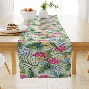 Detail showing tropical floral pattern on linen table runner with green leaves and pink flowers