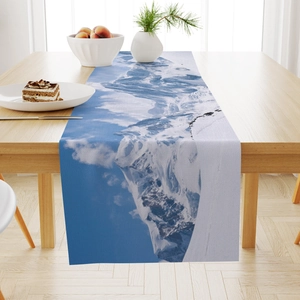 Linen table runner with blue mountain landscape print on a light wooden dining table