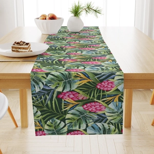 Close-up of tropical palm leaves and exotic flowers printed on a linen table runner