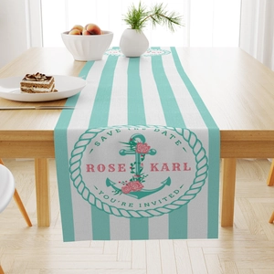 Detail of nautical linen table runner with mint green stripes and vintage anchor emblem