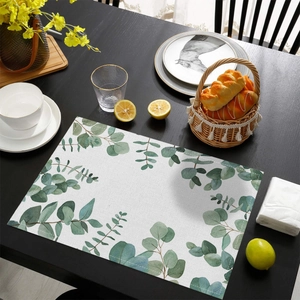 Détail d'un set de table en lin et coton avec imprimé eucalyptus sur table en bois