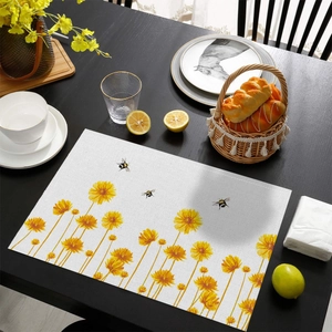 Détail d'un set de table en lin avec imprimé fleurs jaunes et abeilles sur table en bois