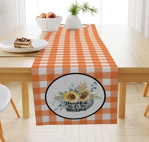 Detail of Thankful & Blessed text on orange checkered autumn table runner with sunflowers