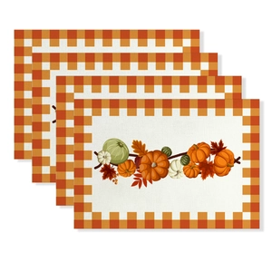 Detailed view of four autumn placemats with pumpkins, maple leaves, and orange plaid borders