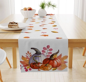 Close-up of autumn table runner with pumpkins and maple leaves on a linen texture