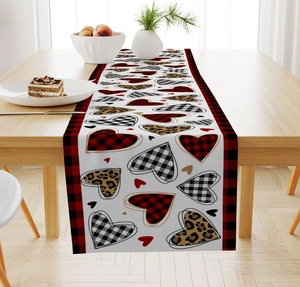 Detail of linen table runner with heart prints and red black plaid edges on wood table