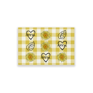 Macro detail of yellow gingham placemat with sunflower, heart and leaf prints