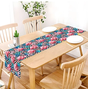 Detail of tropical flamingo and palm leaf print table runner on a wooden dining table