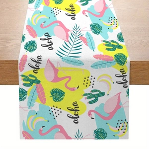Linen table runner with tropical flamingo and palm leaf print on a wooden table