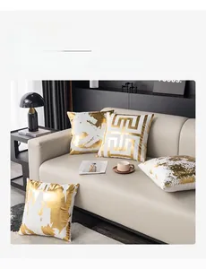Détail de housses de coussin dorées avec motifs géométriques sur un canapé beige moderne