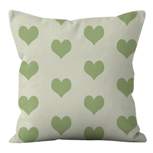 Close-up of square cushion cover with green heart pattern on soft fabric texture