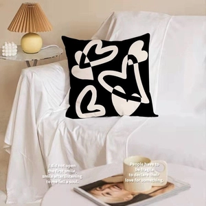 Nordic black square throw pillow with white heart line art on a cozy sofa setting