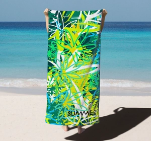 Detail view of microfiber beach towel featuring vibrant green tropical leaf patterns and SUMMER text