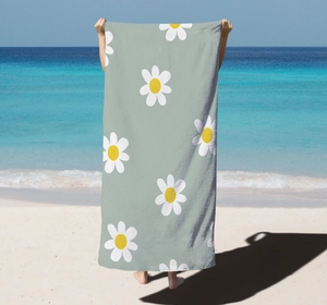 Detail view of a large microfiber beach towel featuring a white daisy floral print on green