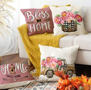 Detail of four fall themed linen pillow covers with floral and text prints on a cozy sofa