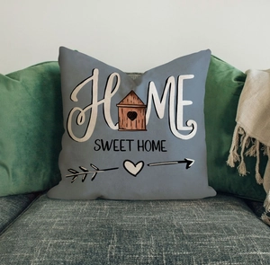 Close-up of gray linen pillowcase with Home Sweet Home text on a textured sofa