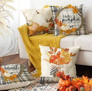 Detail of four linen fall pillow covers with pumpkins and maple leaves on a white sofa