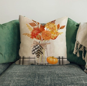 Close-up of autumn linen pillowcase with pumpkin and maple leaf patterns on a grey sofa
