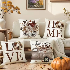 Detail of four linen fall pillow covers with pumpkin designs on a cozy sofa