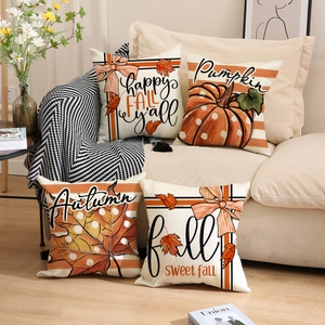 Detail of four autumn throw pillows with pumpkins and maple leaves on a sofa