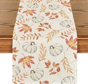 Close-up of autumn linen table runner with white pumpkin and maple leaf patterns