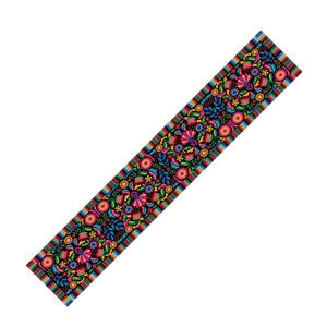 Detailed view of colorful Mexican floral embroidery on black fabric table runner
