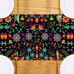 Detailed top view of a black table runner with vibrant Mexican floral patterns and cutlery