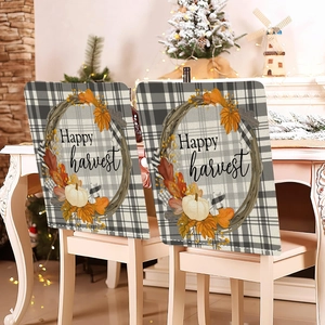 Detail of harvest pumpkin dining chair covers with Happy Harvest text on plaid fabric