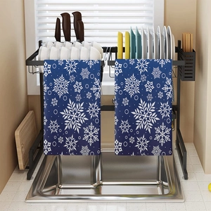 Dettaglio di asciugamani da cucina blu con fiocchi di neve appesi a uno scolapiatti nero