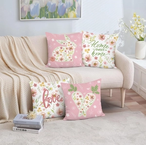 Close-up of four Easter pillow covers with pink rabbits and floral heart patterns on sofa