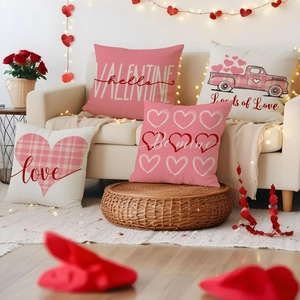 Detail of four Valentine pillow covers with pink truck and heart designs on a white sofa