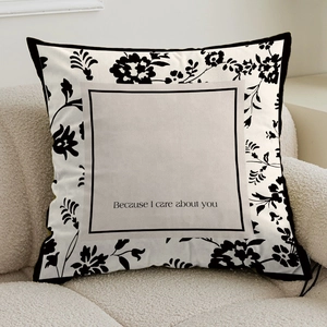 French cream style square throw pillow with black floral patterns and text on a cozy sofa