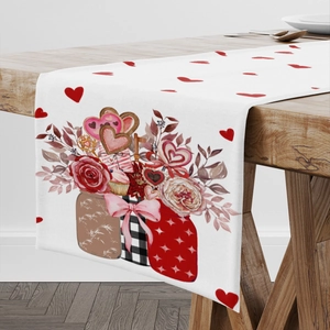 Valentine's Day table runner with red roses and hearts on white fabric over wooden table