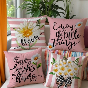 Set of four spring decorative linen pillows with daisy prints and letters on white sofa
