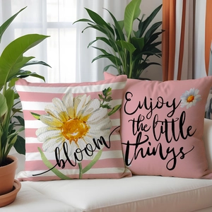 Detail of linen pillow covers with daisy prints and bloom text on a white sofa