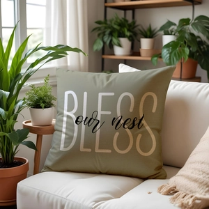 Olive green throw pillow with 'BLESS our nest' print on a white sofa with plants