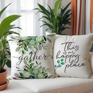Détails de housses de coussin en lin beige avec motifs de plantes et texte Gather brodé