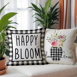 Detail of linen pillow covers with Happy Bloom print and floral bouquet on a white sofa