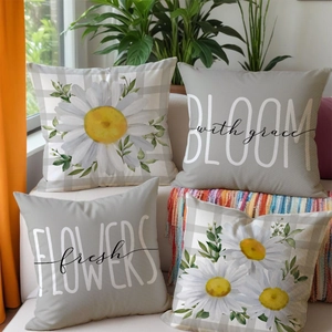 Close-up of four linen pillow covers with white daisy floral and typography prints