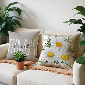 Close-up of linen pillow covers featuring white daisy prints and decorative flower text