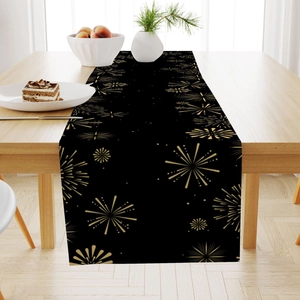 Detail of black and gold firework festive table runner on a wooden dining table