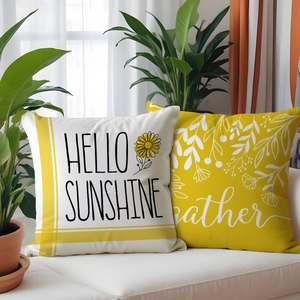 Detail of two floral sunflower pillow covers with Hello Sunshine text on a white sofa