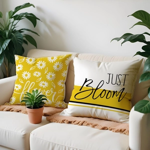 Detail of linen pillow covers with daisy prints and JUST Bloom text on a sofa